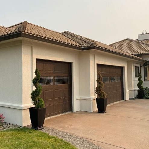 A garage featuring two doors, situated alongside a neatly paved driveway, showcasing a well-maintained exterior