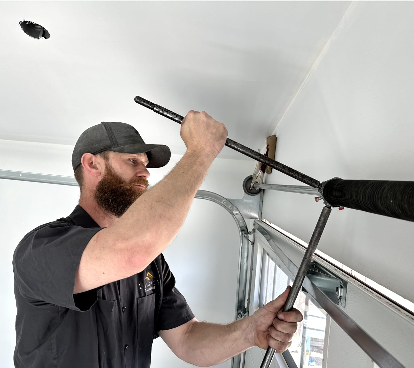 A man repairs a garage door using a tool, demonstrating skill and focus in his task