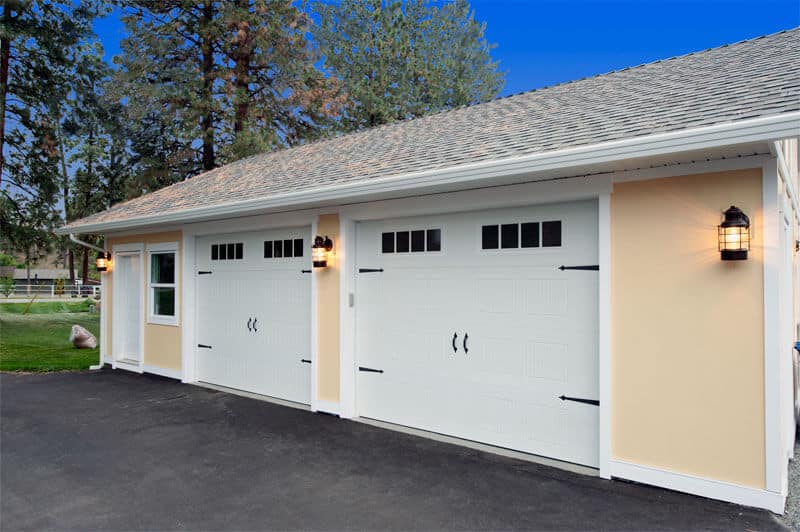 CarriageCraft residential garage door by Legacy Garage Doors in Kelowna, featuring a traditional carriage-style design with decorative hinges and wood grain texture