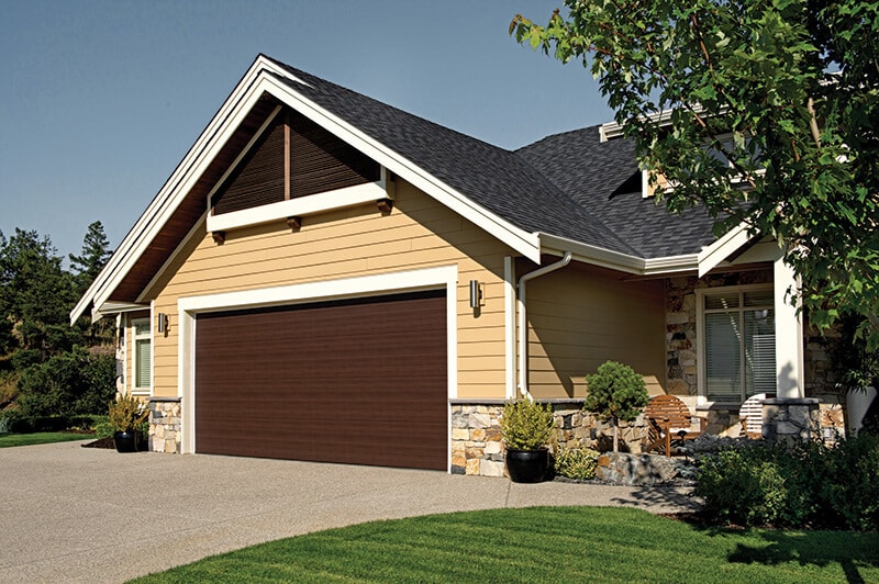 Contemporary residential garage door by Legacy Garage Doors in Kelowna, featuring a sleek, modern design with large glass panels and aluminum framing