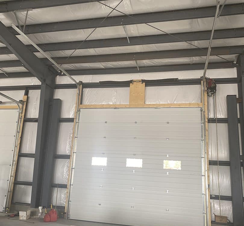Inside view of a 16x14-foot steel garage door with a high-lift system, showing the backing and support structure