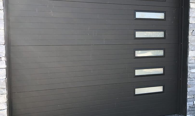 harcoal-colored contemporary garage door featuring stacked narrow glass panels and a sleek right-hand section design for modern homes