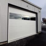 Steel garage door with sectional glass panels, designed for commercial buildings, blending durability with modern aesthetics