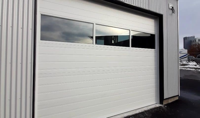 Steel garage door with sectional glass panels, designed for commercial buildings, blending durability with modern aesthetics