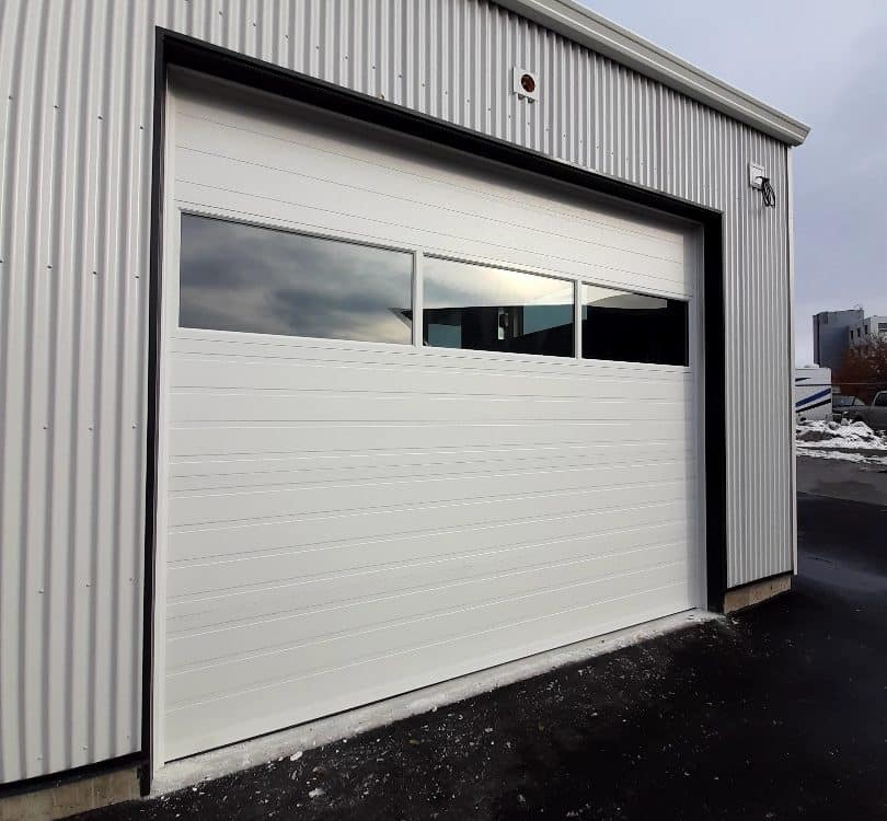 Steel garage door with sectional glass panels, designed for commercial buildings, blending durability with modern aesthetics